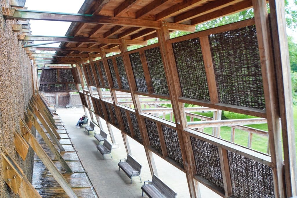 Ein überdachter Gang am Gradierwerk Bad Sassendorf mit Holzbänken entlang einer mit Reisig gefüllten Wand, an der Sole herabrieselt.