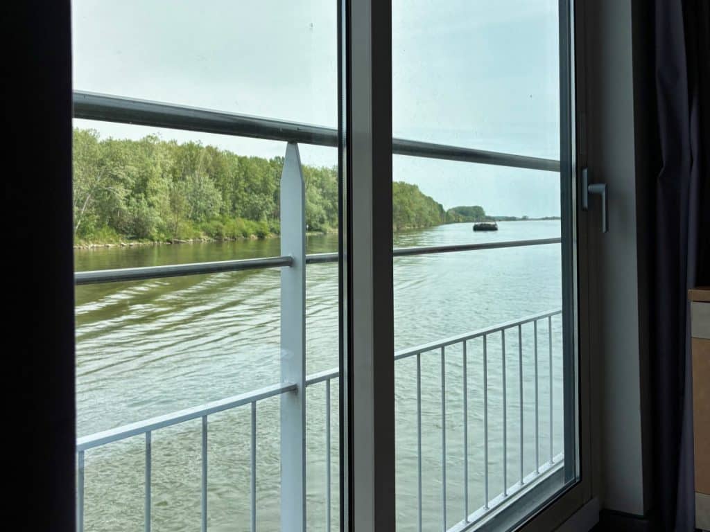 Blick aus dem Fenster einer Kabine auf der Maxima auf den Fluss und das bewaldete Ufer.