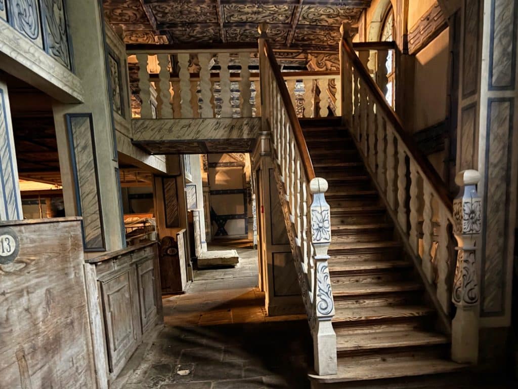 Eine hölzerne Treppe mit kunstvoll verzierten Geländern führt in der Friedenskirche von Jawor in Niederschlesien hinauf zu einer Empore unter einer reich bemalten Kassettendecke.