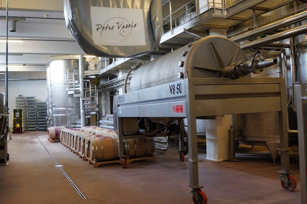 Innenansicht einer Fertigungshalle des Weinguts Petro Vaselo in der Region Timis mit großen Edelstahltanks, einer VS 50 Weinpresse und aufgereihten Holzfässern.