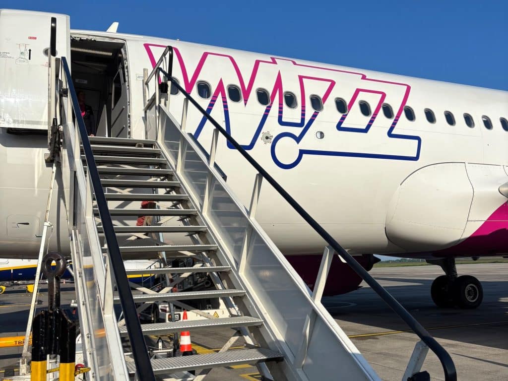 Eine Nahaufnahme eines Wizz Air Flugzeugs in Rumänien während des Boarding-Vorgangs, bei dem eine mobile Treppe direkt zur offenen Flugzeugtür führt.