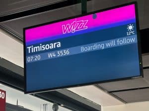 Ein digitaler Informationsbildschirm am Flugsteig zeigt den Wizz Air Flug W4 3536 nach Timisoara, Rumänien, mit der Abflugzeit 07:20 Uhr und dem Hinweis „Boarding will follow“.