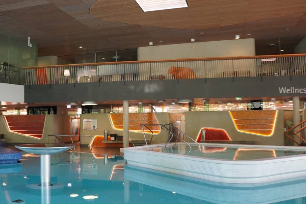 Innenansicht der Emser Therme in Bad Ems mit einem kleinen, erhöhten Thermalbecken im Vordergrund und einem modernen Wellnessbereich auf einer Galerie im Hintergrund.