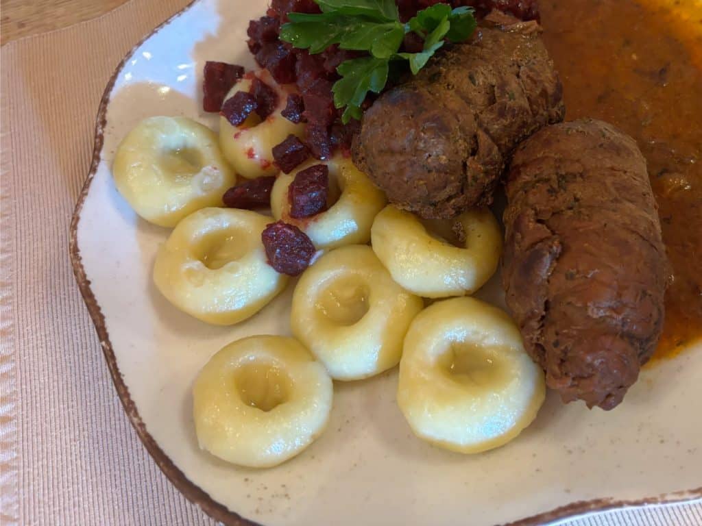 Ein Teller mit einem Tagesgericht der Villa Greta in Niederschlesien, bestehend aus zwei gefüllten Rinderrouladen in dunkler Soße, schlesischen Kartoffelklößen mit typischer Vertiefung und gewürfelten Roten Bete mit Petersiliengarnitur.