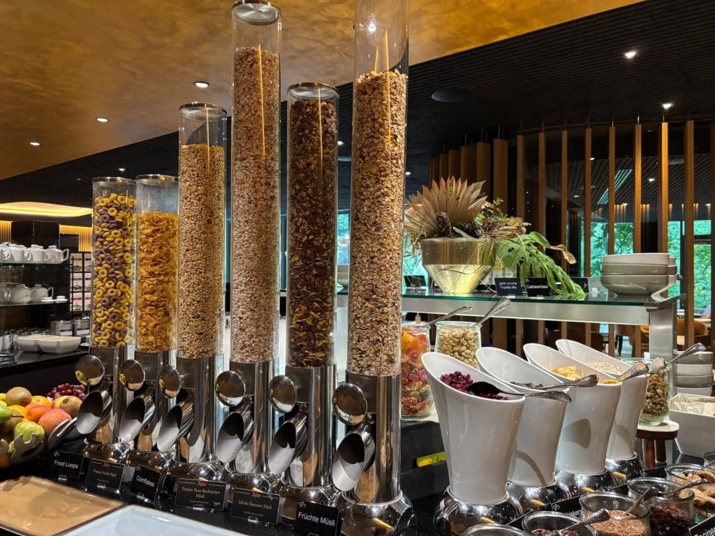 Ein reichhaltiges Frühstücksbuffet im Hotel in Bad Ems mit verschiedenen Müsli- und Getreidesorten in hohen Glaszylindern sowie Schalen mit Trockenfrüchten, Nüssen und frischem Obst.