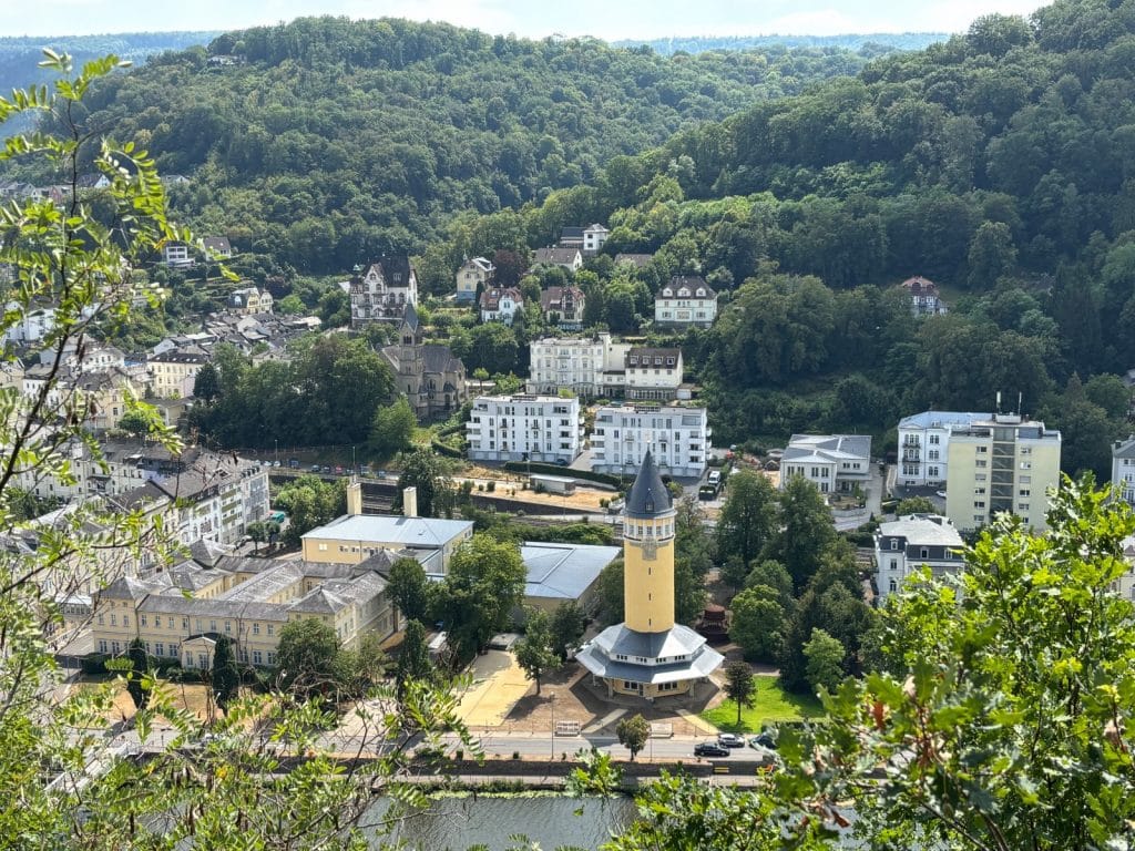 Blick vom Aussichtspunkt Vogler auf das Stadtgebiet von Bad Ems mit dem markanten gelben Wasserturm im Vordergrund, umgeben von historischen Gebäuden und bewaldeten Hängen.