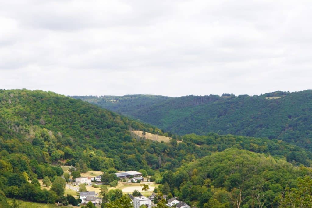 Blick vom Concordiaturm bei Bad Ems auf eine bewaldete Hügellandschaft mit vereinzelten Häusern im Tal unter einem bewölkten Himmel.