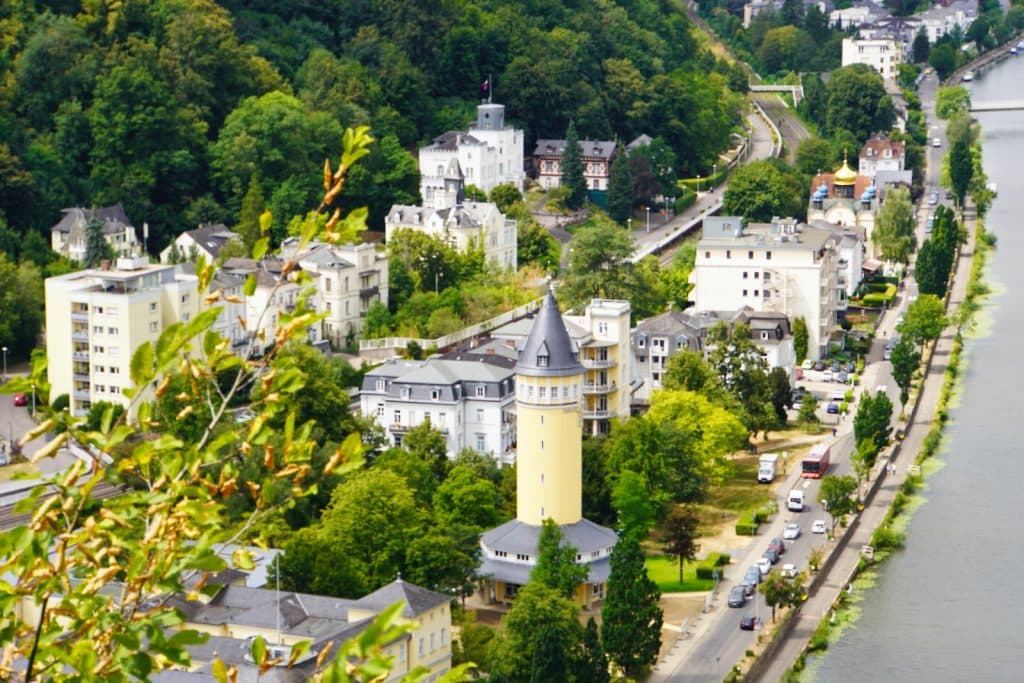 Blick von der Mooshütte auf das Stadtgebiet von Bad Ems mit dem markanten gelben Wasserturm, historischen Gebäuden und der Lahn im Hintergrund.