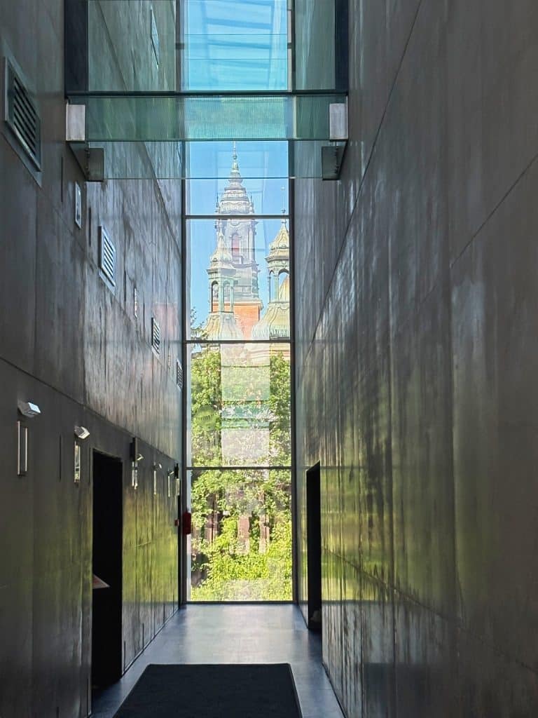 Blick durch eine schmale, moderne Glasspalte im interaktiven Geschichtszentrum Brama Poznania in Posen auf die historischen Türme des Posener Doms.
