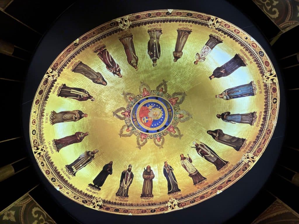 Blick nach oben in die goldene Kuppel der virtuellen goldenen Kapelle in der Brama Poznania, die im Kreis angeordnete Heiligenfiguren auf einem glänzenden Goldgrund zeigt.